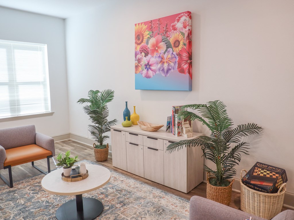 a living room with a table and chairs and a painting on the wall