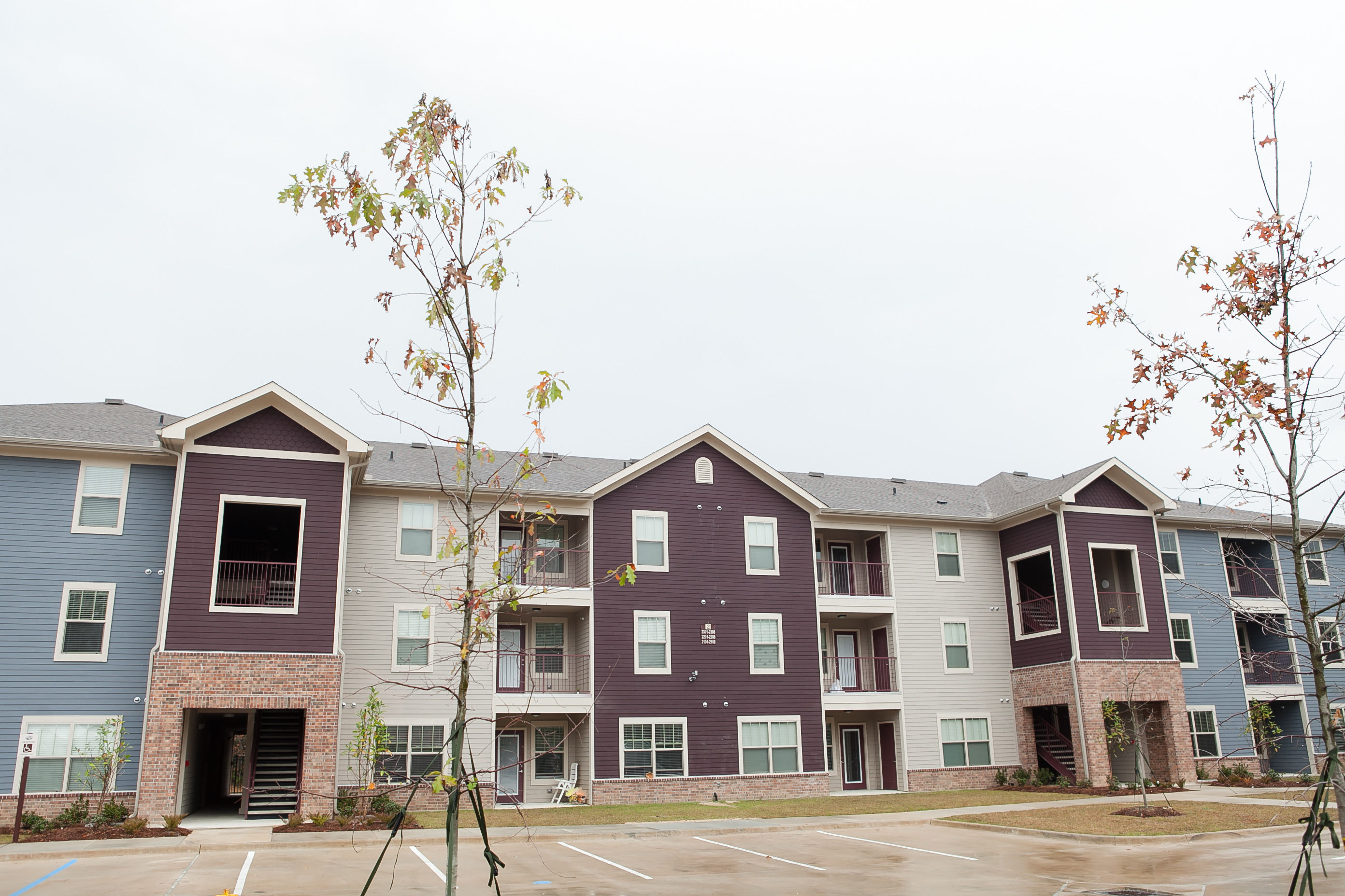 Apartment building with a parking lot in front.