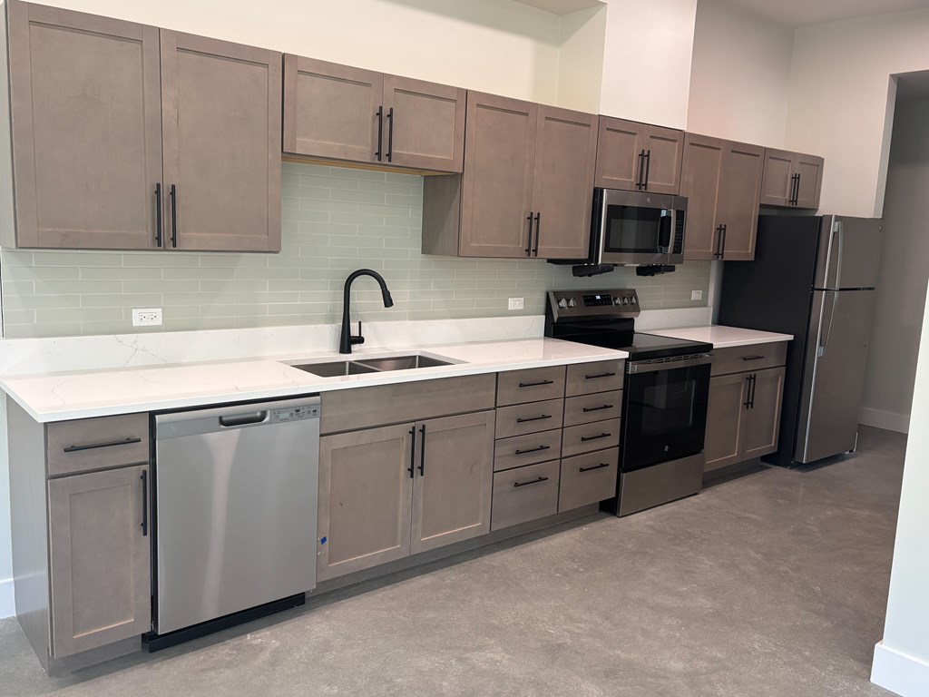 A kitchen with brown cabinets and a black fridge.