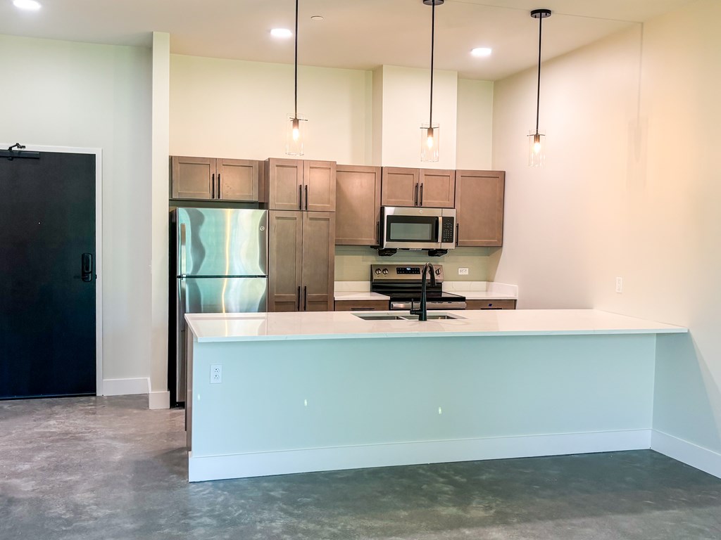 A kitchen with a black refrigerator, brown cabinets, and a white countertop.