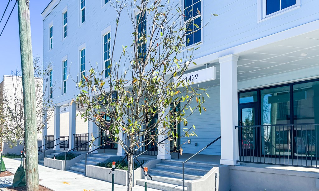 A tree in front of a white building with the number 1429 on it.