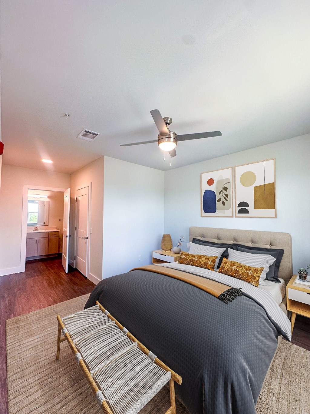 A bedroom with a bed, a bench, and a ceiling fan.