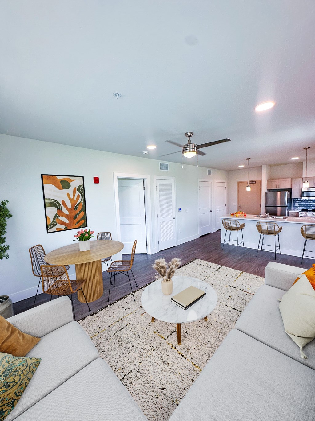 A living room with a white couch and a round table with a plant on it.