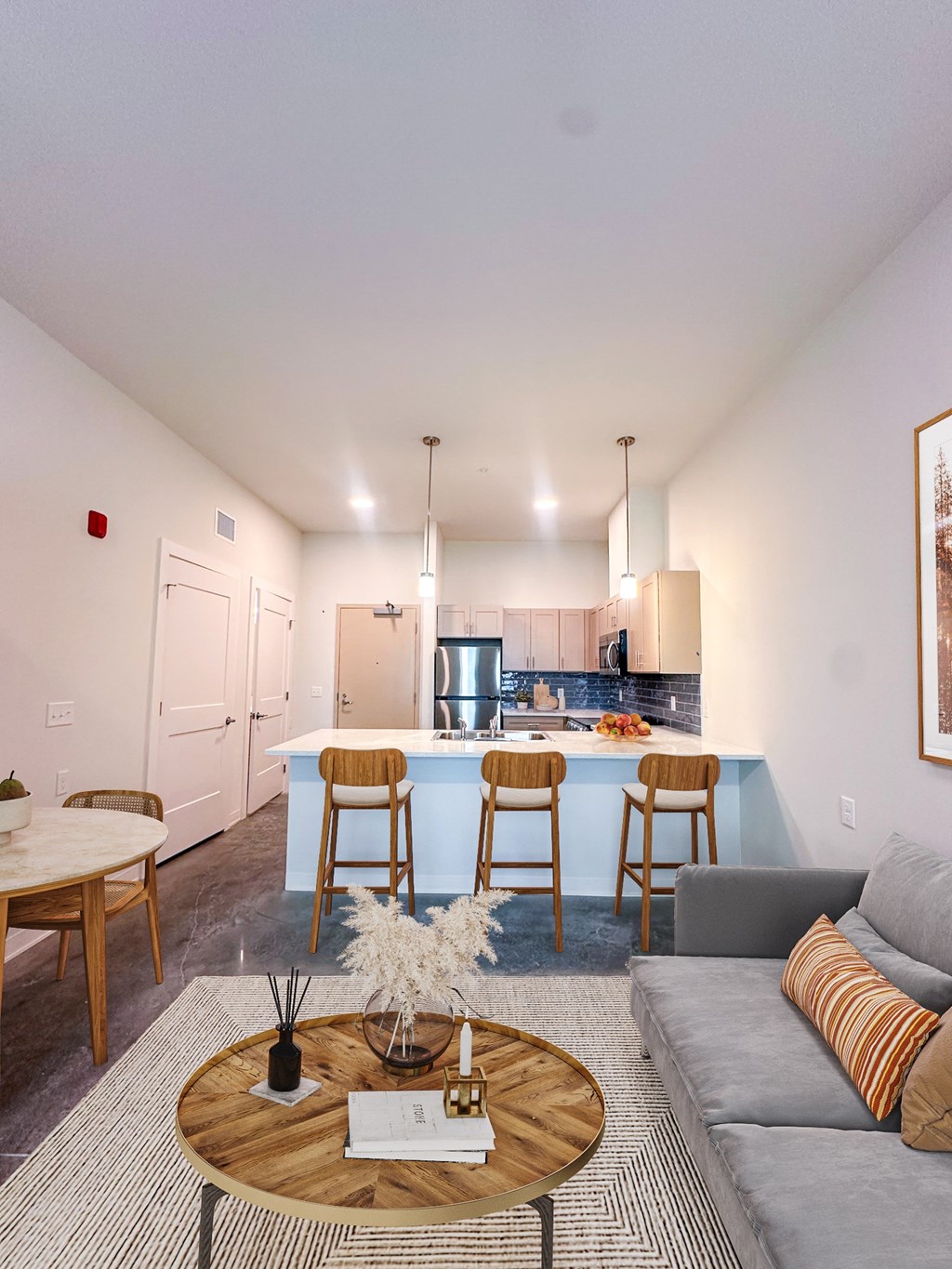 A modern kitchen with a bar stool and a grey sofa.