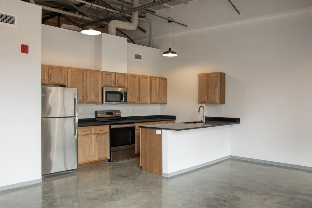 an empty kitchen with stainless steel appliances and wooden cabinets