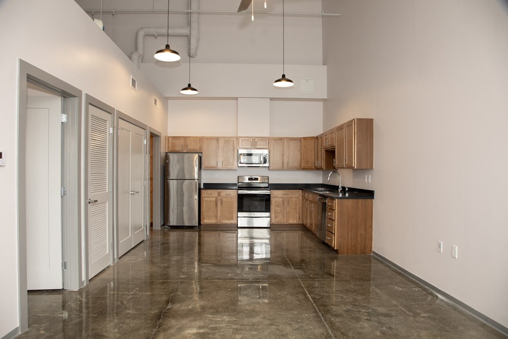 an empty kitchen with stainless steel appliances and wooden cabinets