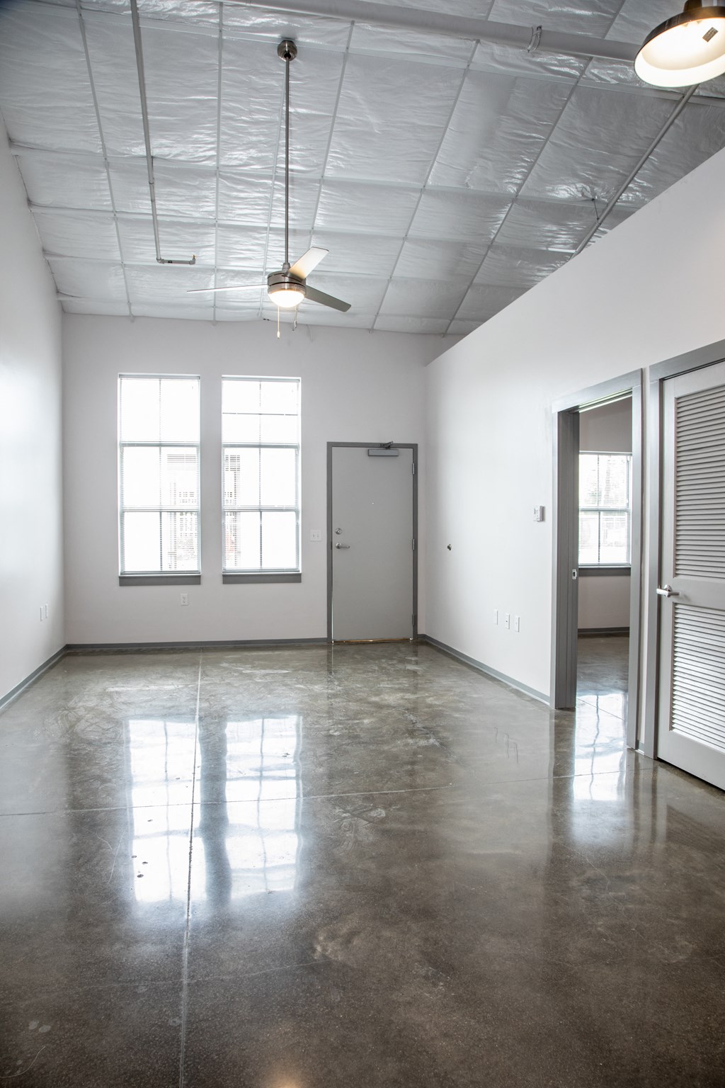 an empty room with white walls and a door and a ceiling fan