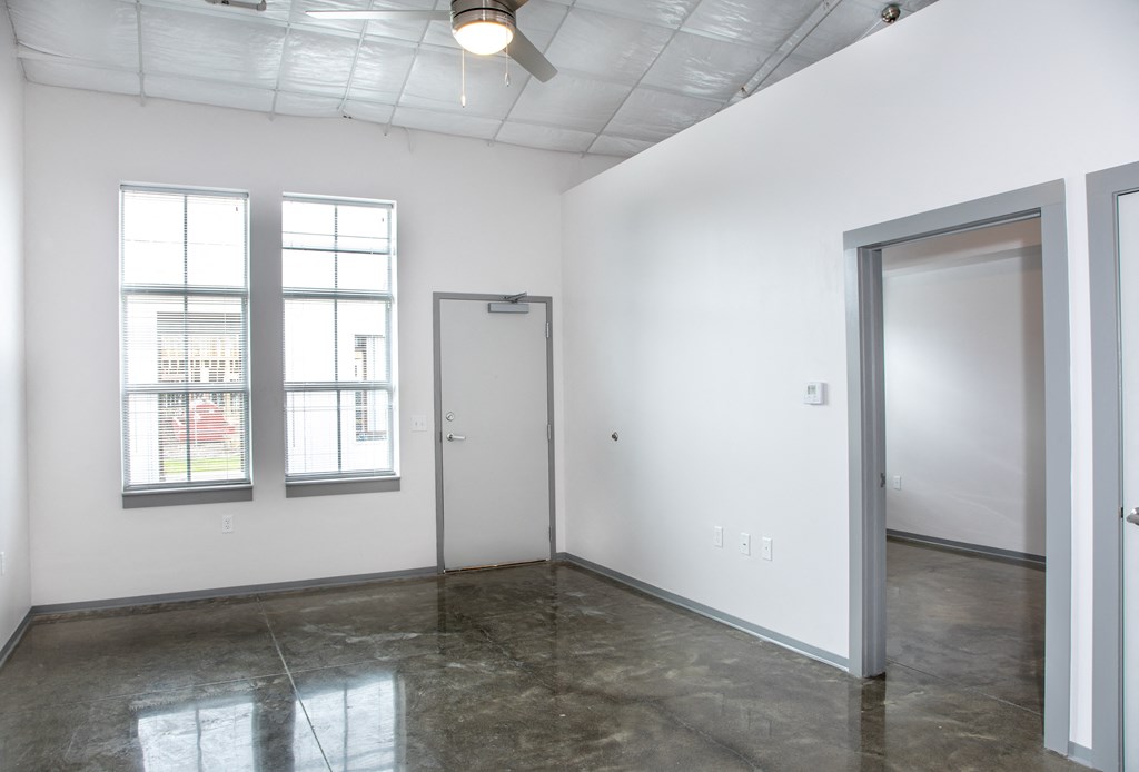 an empty room with two windows and a door