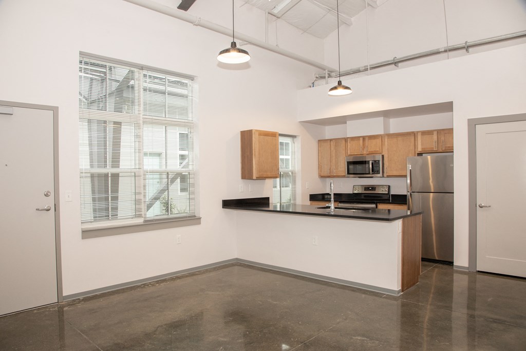 an empty kitchen with a large window and a stainless steel refrigerator