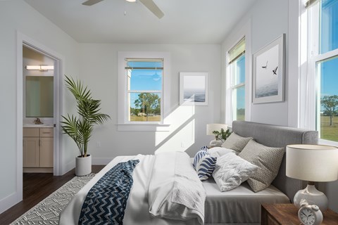 A bedroom with a bed, a ceiling fan, and a potted plant.