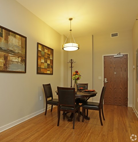 A dining room with a table set for two and a chandelier hanging from the ceiling.