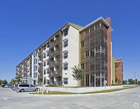 A modern multi-story building with a parking lot in front.