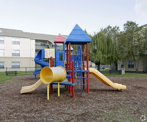 A playground with a yellow slide and a blue roofed structure.