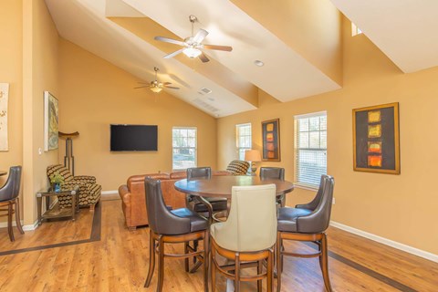 A living room with a television and a dining table with chairs.