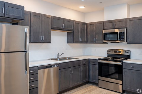 A modern kitchen with dark wood cabinets and stainless steel appliances.
