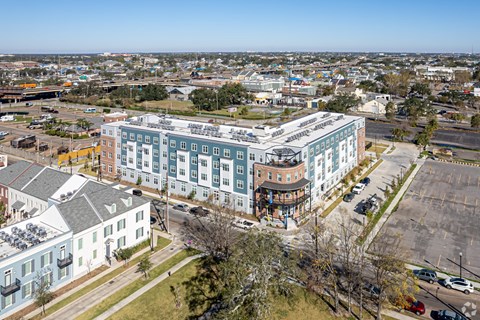 A large building with a green roof is in the center of a parking lot.
