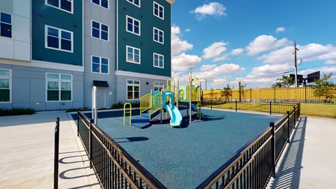 A playground with a blue slide and a yellow slide in front of a building.