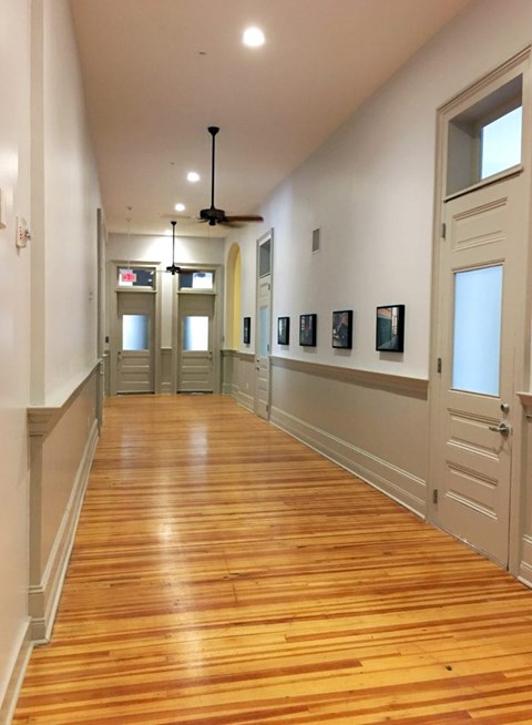 A long hallway with wood floors and white walls.