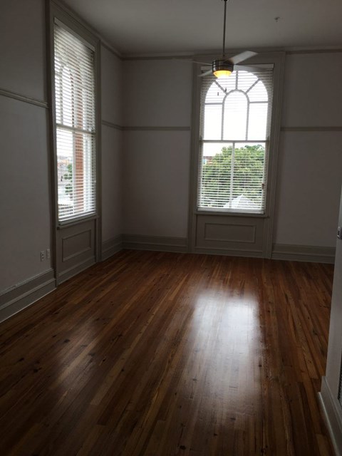 A room with wooden floors and a large window with blinds.