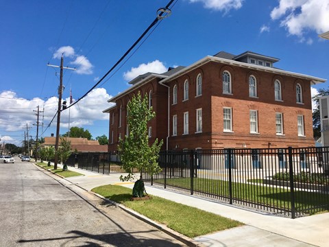 A red brick building with a black fence in front.