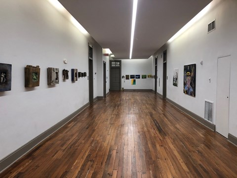 A hallway with wood floors and pictures on the wall.