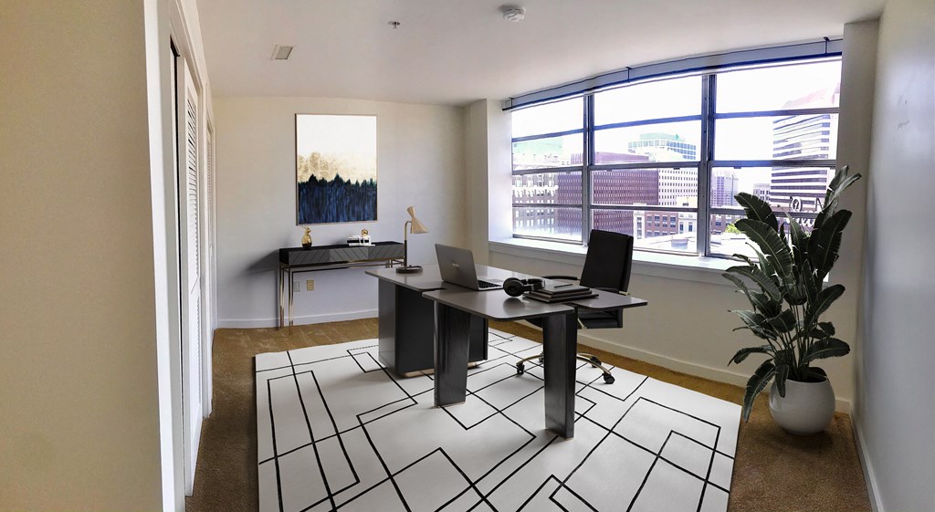 a home office with a large window and a desk with a laptop