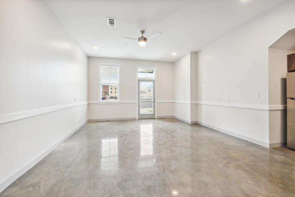 A spacious room with a ceiling fan and a large window.