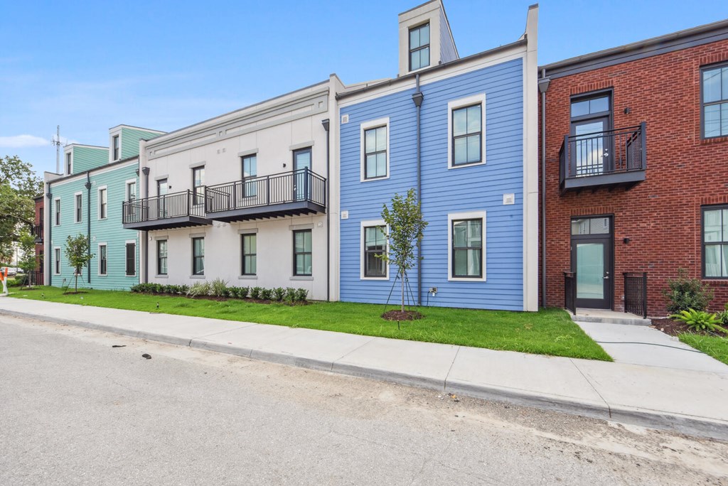 A row of three-story townhouses with balconies and front yards.