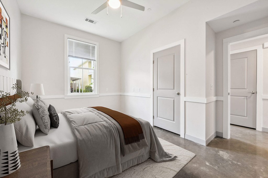 A bedroom with a bed, a ceiling fan, and a window.