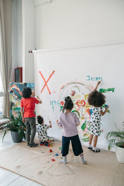 a group of children painting on a white wall