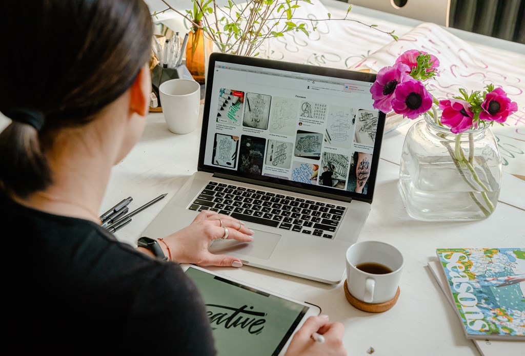 a woman sitting at a table using a laptop computer
