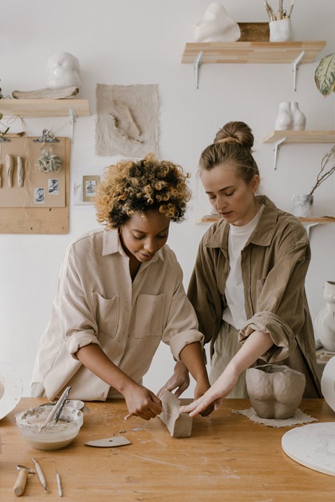 two women in a ceramics workshop making a piece of pottery