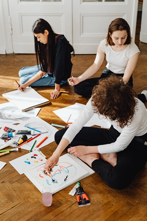 three women sitting on the floor collaborating on a drawing