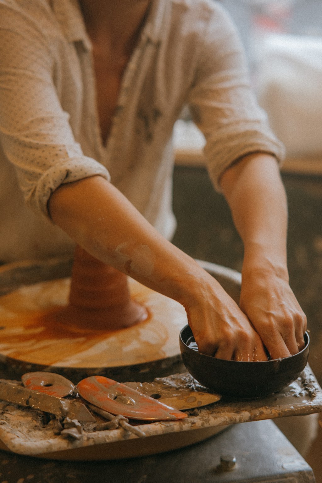 a woman shaping clay on a pottery wheel with her hands