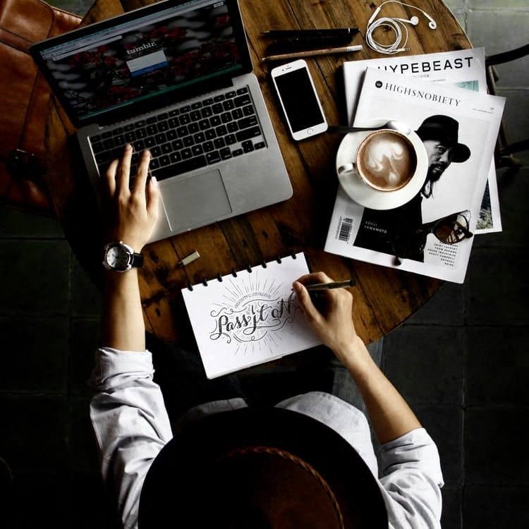 a person sitting at a table with a laptop and a cup of coffee