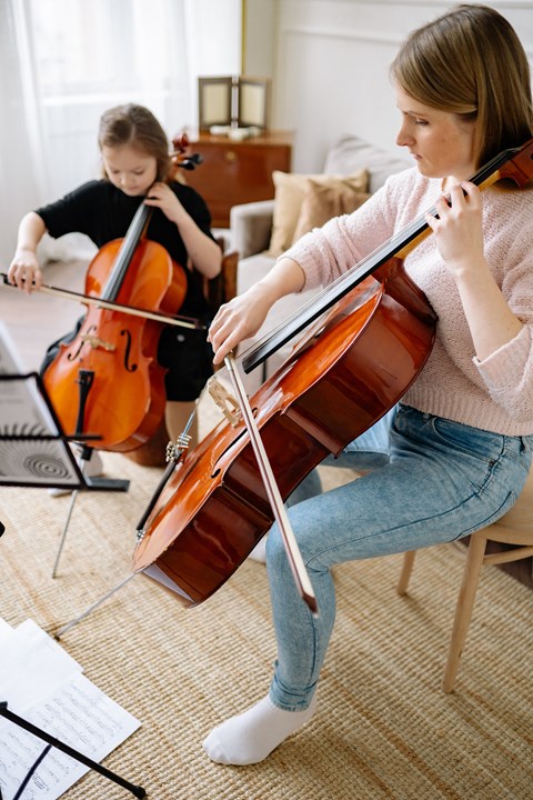 two girls playing violin in a living room