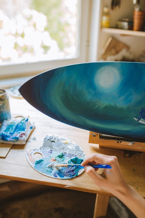 a person painting a bowl on a table with a work of art