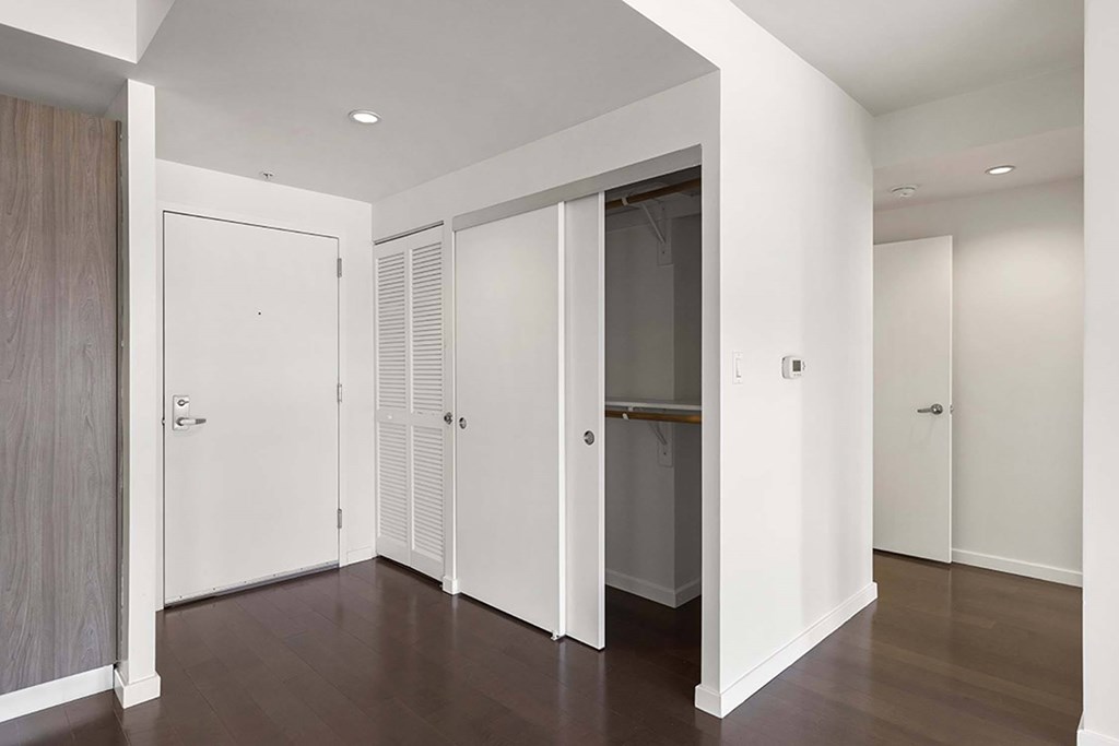 A hallway with white doors and a wooden floor.