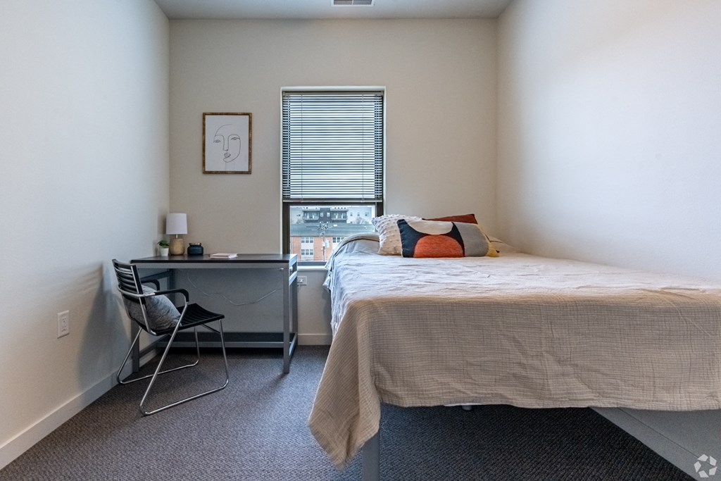 a bedroom with a bed and a desk and a window