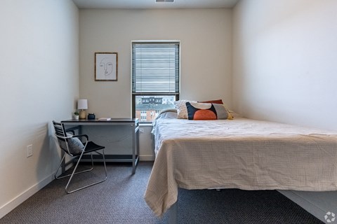 a bedroom with a bed and a desk and a window