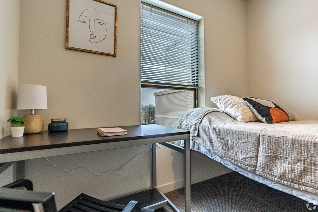 a bedroom with a bed and a desk and a window