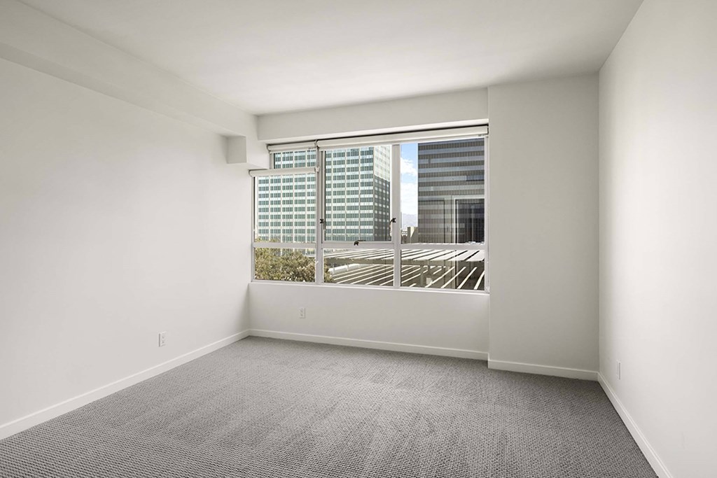 A large empty room with a window overlooking a parking lot.