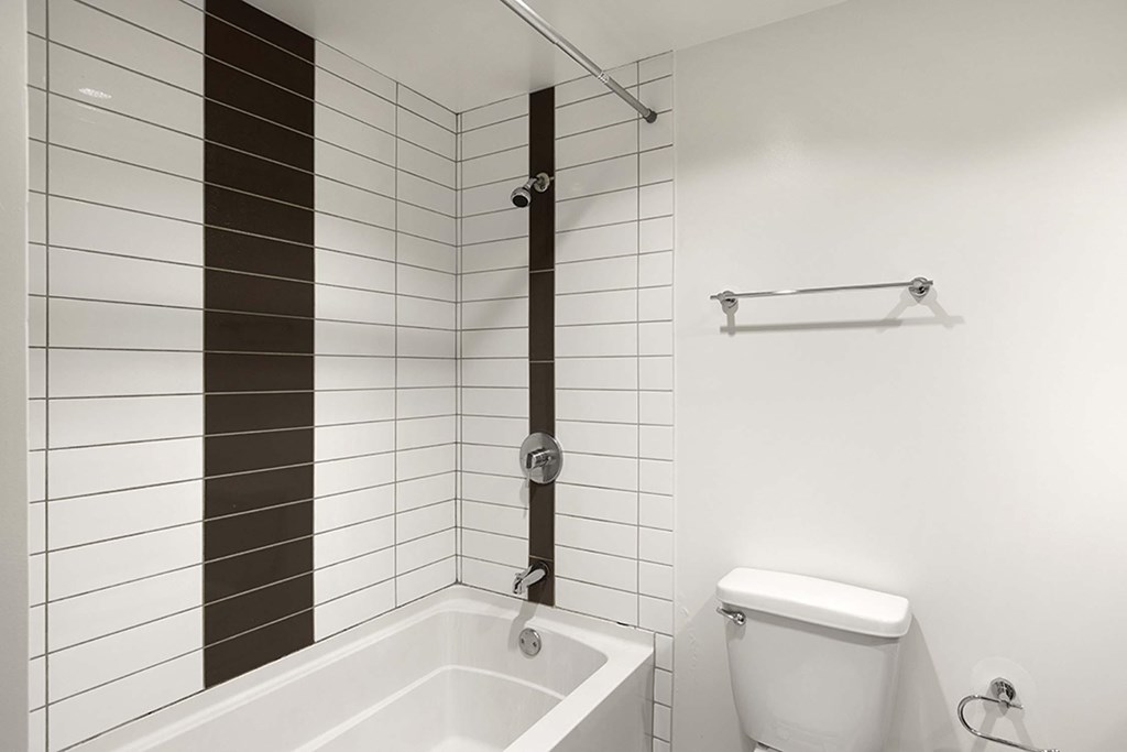 A white toilet sits next to a white bathtub in a bathroom.