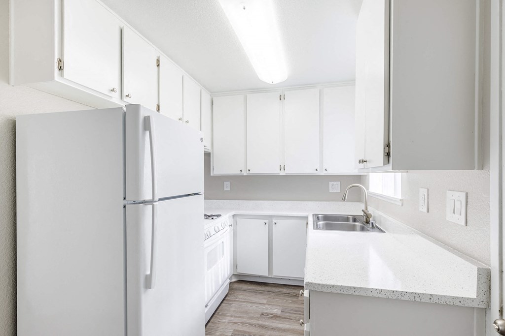 a white kitchen with white cabinets and a white refrigerator