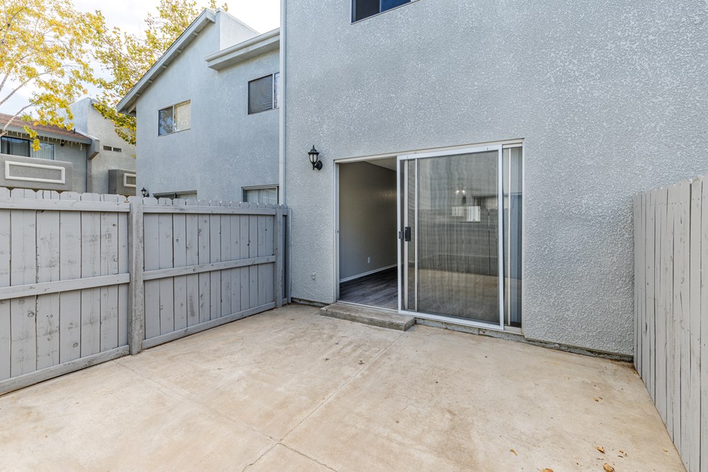 a patio with a fence and a house with a sliding glass door