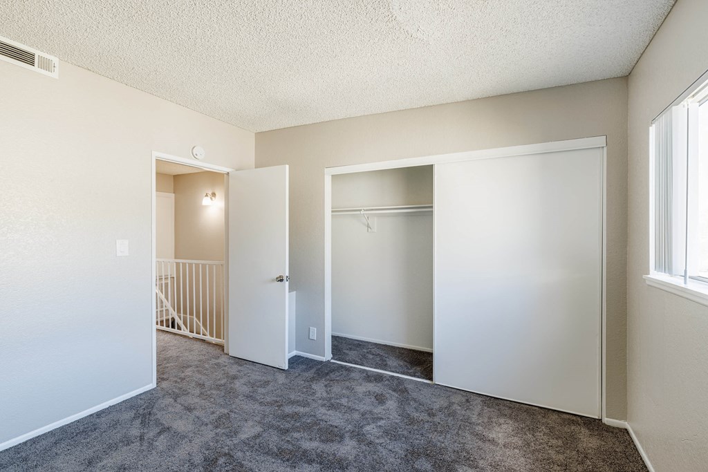an empty living room with an open door to a closet