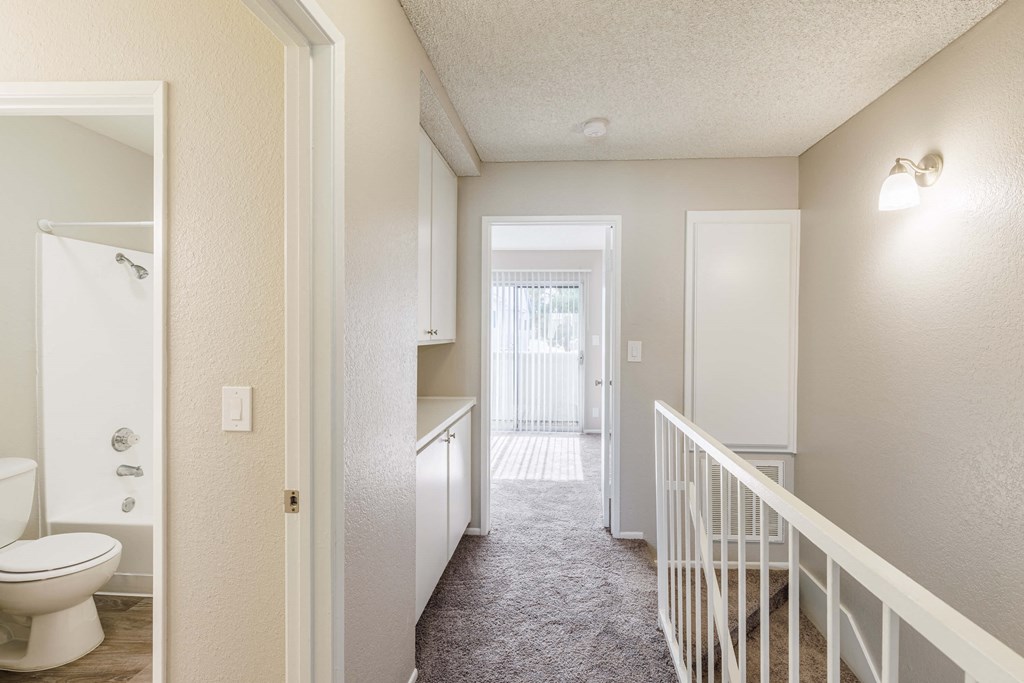 a renovated bathroom and hallway with a staircase and a toilet and a shower