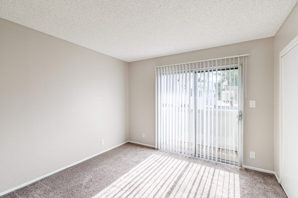 an empty living room with a sliding glass door to a patio