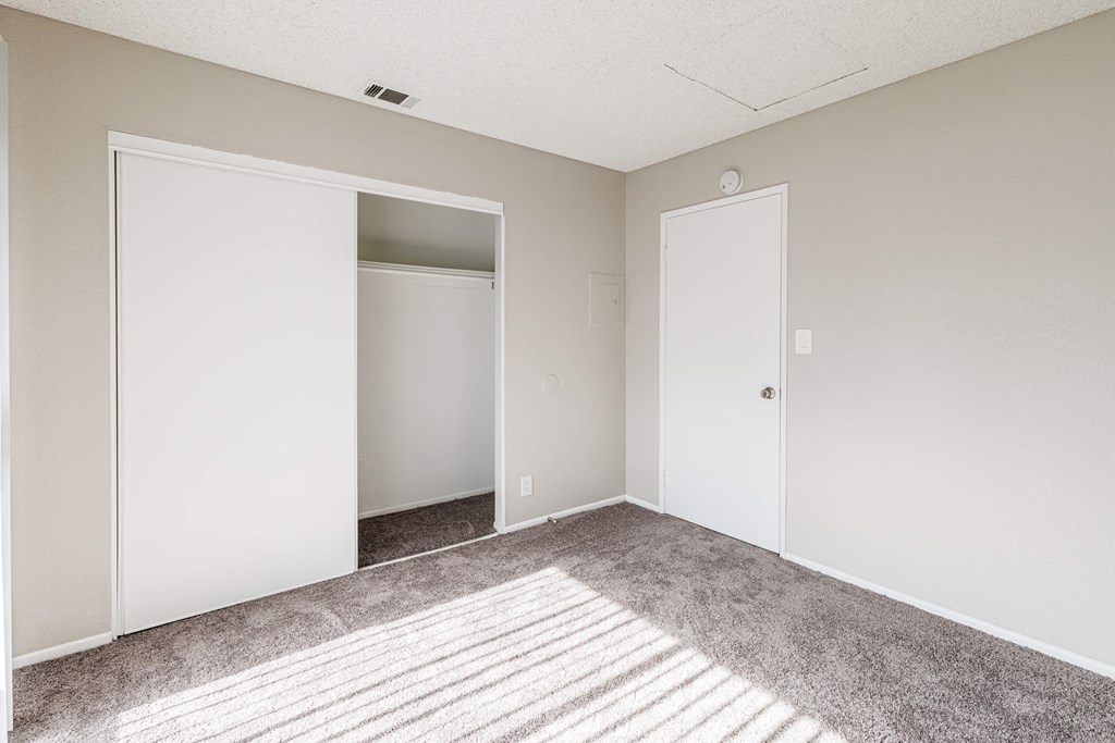 an empty bedroom with a carpeted floor and a closet