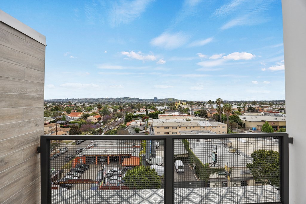 a balcony with a black railing and a view of a city at The Fairfax Flats Apartments, Los Angeles, CA